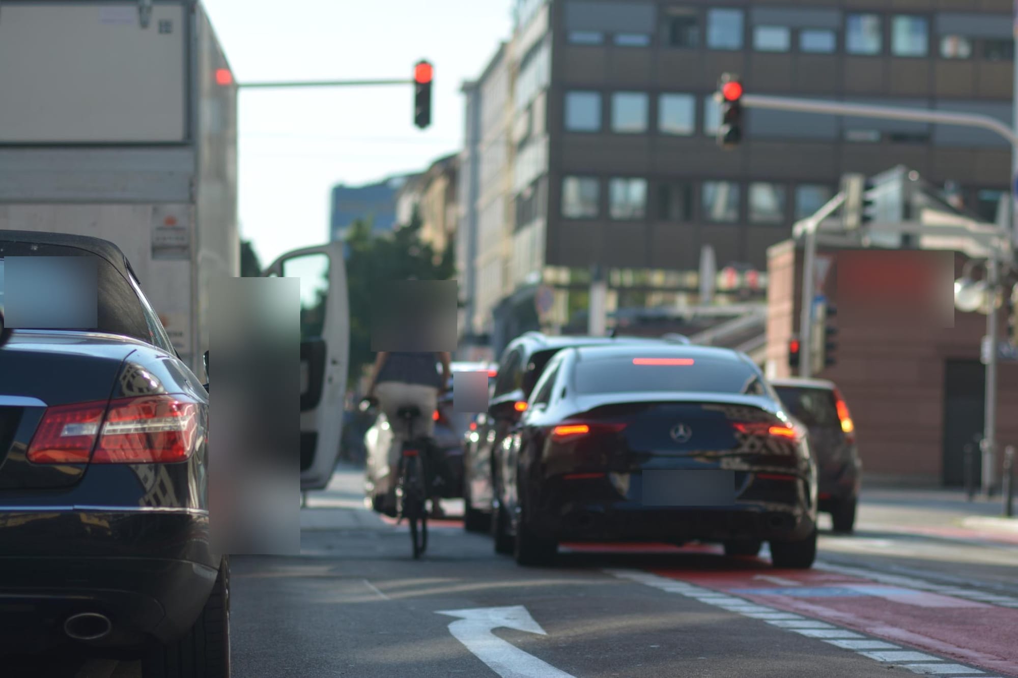 Radfahrerin in Gefahr - in der Halteverbotzone links öffnet ein LKW-Beifahrer die Tür, rechts von der Radfahrer*in eine Autoschlange, die sich durch die eigentlich verkehrsberuhigte Zone drängelt.