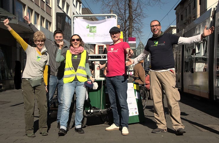 5 Aktive, die sich riesig freuen in der Breiten Straße vor ihrem Banner