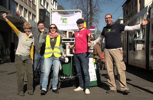 5 Aktive, die sich riesig freuen in der Breiten Straße vor ihrem Banner