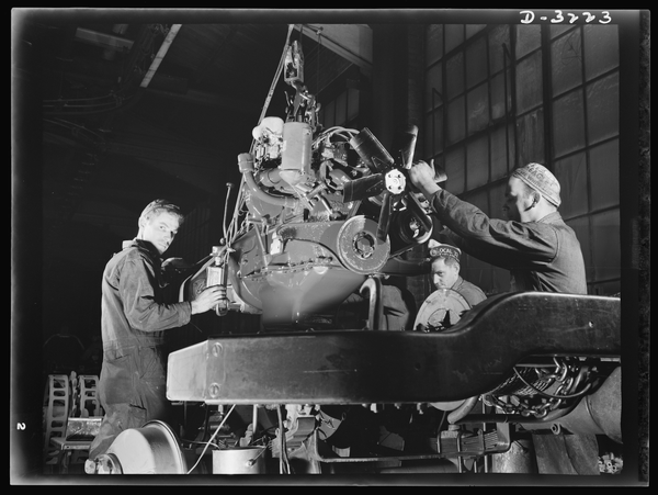 Altes Schwarzweißbild (möglicherweise aus den 50ern?) das zeigt, wie ein Motor montiert wird